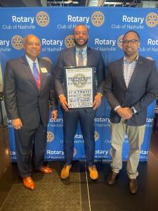 Attorney Corbin Carpenter standing in the center of two supporters holding a certificate of membership into Rotary Club of Nashville