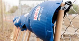 Syncon LLC construction helmet hung on a fence with the logo WATA and Syncon on the side