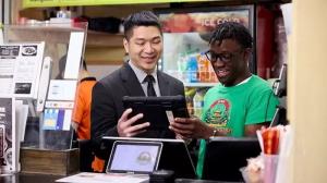 Patrick Cheng and a staff member smiling while reviewing a tablet at the restaurant’s front counter, showing the use of digital systems.