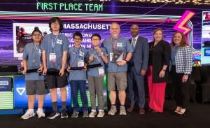 4 middle school students holding trophies and their coach holding a plaque posing with representatives from MATHCOUNTS and their sponsors.