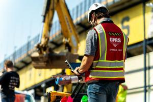 A GPRS Project Manager pushing a ground penetrating radar cart on a construction site.