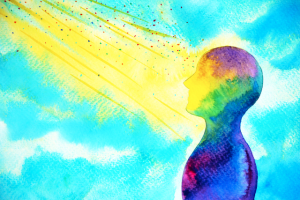 Watercolor painting of a human silhouette in rainbow tones looking toward radiant yellow light beams on a bright blue background, representing mindfulness and emotional healing.