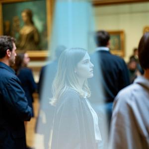A woman at a museum enjoys a private audio experience through a directional speaker system, demonstrating how focused sound zones improve clarity without adding ambient noise.