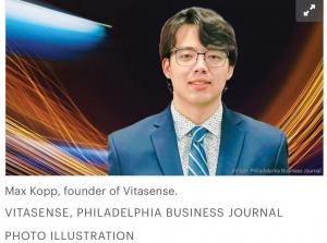 Portrait of Max Kopp in a blue suit and tie standing against a backdrop of dynamic orange and blue light trails, announcing his inclusion in Philly Inno’s 25 Under 25 Class of 202