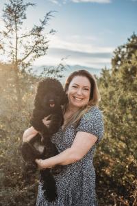 Corinne Gearhart, certified Doodle trainer and author of Your Doodle’s Daily Schedule Blueprint™, pictured outdoors in the Colorado mountains with her Cavapoo, Nestlé.
