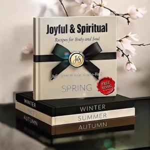 Stack of hardcover books from the Joyful & Spiritual series arranged by season, with the Spring Edition displayed on top. Includes a “Free Song” badge, elegant design, and cherry blossom backdrop to reflect renewal and faith.