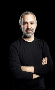 Headshot style image of Andrew Nemr photographed against a black background wearing a black shirt