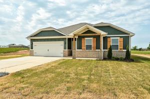 One-story green exterior home at 5345 Little Foot Lane with front porch, white garage door, and Craftsman detailing by Craft Homes in Guthrie, OK.