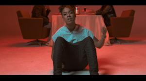 Ray Gifted Keys sits in a red-lit scene, captured in an emotional moment from the “Wrong One” music video.