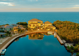 Picture of three-story resort Inn with Caribbean Sea in background glowing golden in Belizean sunset