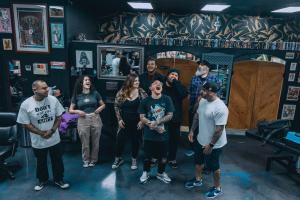 Team members at Golden Child Tattoo & Piercing Shop standing together and laughing in the Escondido, CA studio during a candid moment.