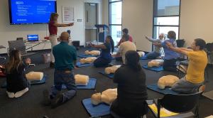 Gail Gould, nationally certified CPR instructor and founder of CPR and Safety Lady, leads a hands-on CPR training session demonstrating chest compressions to participants.