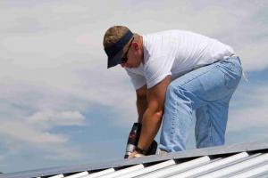 Man on roof holding a drill