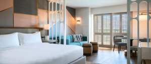Bright, modern hotel room at Renaissance Esmeralda Resort & Spa featuring a queen bed, stylish seating area, and large windows with shutters. Elegant design elements throughout.