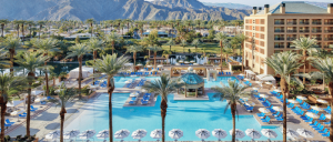 Renaissance Esmeralda Resort & Spa's pool surrounded by palm trees, lounge chairs, and a mountainous backdrop under a clear blue sky.