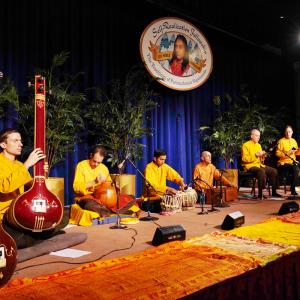 SRF monks playing instruments on stage