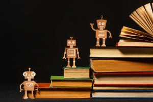 Kitap yığınları üzerinde duran çizim tarzında robot figürleri, yapay zekânın eğitimle birleşimini temsil ediyor.