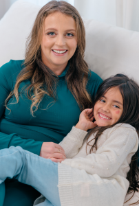 Candice Kelly, founder of Lunchbox Hero, sits smiling with her young daughter Tatiana, who inspired the creation of the kid-focused lunch planning platform.