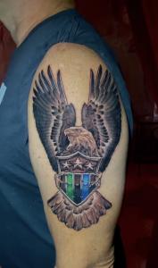 Military-style eagle tattoo holding a shield with stars and stripes, created by Nashville-based tattooist Elvis.