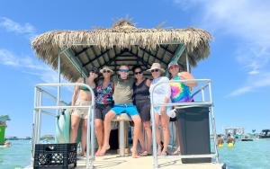 Six people enjoying themselves on a Crab Island Journeys Tiki Cruise Boat.