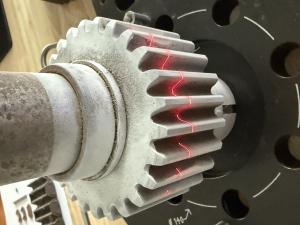 Close-up of a Hexagon Absolute Arm laser scanning a gear tooth, capturing its precise geometry for inspection and quality control.