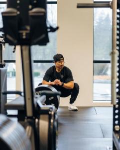 Danny Tran stretching on a gym floor at Industrious Puyallup, surrounded by fitness equipment.