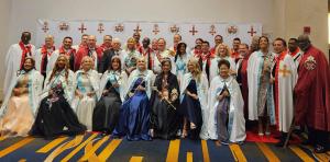 Group photo of the Knights and Dames of the Royal Order of Constantine the Great and Saint Helen dressed in ceremonial robes and regalia. The members, representing global leadership, philanthropy, and service, pose after the Investiture Ceremony. A banner