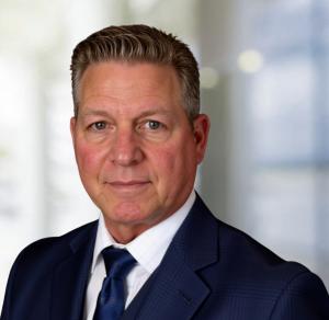 Formal headshot man in dark jacket and tie