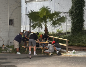 A group of people painting a picnic table.