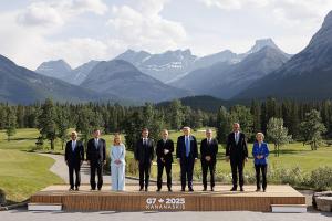 G7 Leaders and guests take a 'family photo' in a single line, dressed in business suits, against the backdrop of the forest and mountains of Kananaskis, Canada