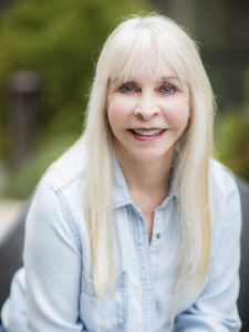 Outdoor portrait of Valerie Heller, spiritual teacher, author, and featured contributor to the international #1 bestselling book Whispers of the Soul: Stories of Resilience, Awakening, and the Power of Healing from Within. She is smiling warmly, wearing a