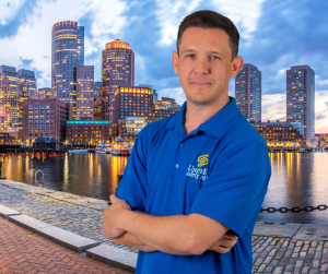 Rony Jabour in front of the Boston skyline, raising awareness about heat safety for construction workers during a record-breaking U.S. heatwave.