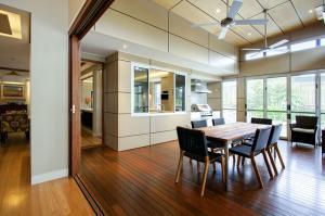 Covered indoor-outdoor dining space with timber flooring, high ceilings, ceiling fans, servery and sliding glass doors, part of a future-proof home renovation in Indooroopilly by dion seminara architecture.