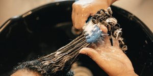 a hairstylist providing hair relaxer treatment