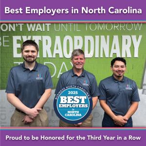Three Heritage Signs & Displays team members standing in front of a wall graphic that reads “Be Extraordinary Today,” wearing company polos and smiling in recognition of the 2025 Best Employers award.