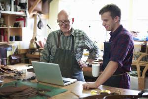 Two small business owners looking at a laptop and considering their cybersecurity practices and regulatory compliance.