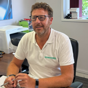 Tom Hamlett of Godiva Bearings sitting at desk, working wearing a Godiva Bearings white polo shirt