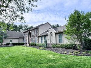 Suburban stucco and brick home with green grass lawn in front