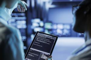 Two business owners looking at code on a tablet in a data center.