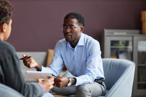 Psychiatrist leaning forward and speaking with patient