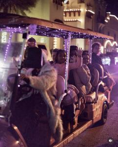 Guests wave from a Pink Culture golf cart lit with pink lights during the St. Augustine Nights of Lights tour