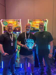 PAKMAN (center) poses with Luke & James Anderson (left, right, respectively) of Alan-1 in front of one of the Missile Command: Recharged arcade cabinets that he won