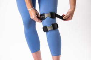 Person putting on a KneeMo® wearable device, demonstrating how easily the device is put on for daily use.