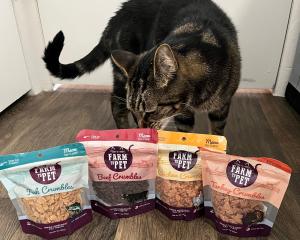 Tabby cat sniffing bags of Farm to Pet Crumbles cat treats.