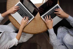 Adults using the Actxa Core Smart Ring in Matt Silver and Matt Black while doing work on their laptop