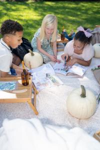 Children at a A Noble Foundation ANF gathering sharing connection  and looking at Noble Adventures Magazine inspiring holistic wellness and educational enrichment